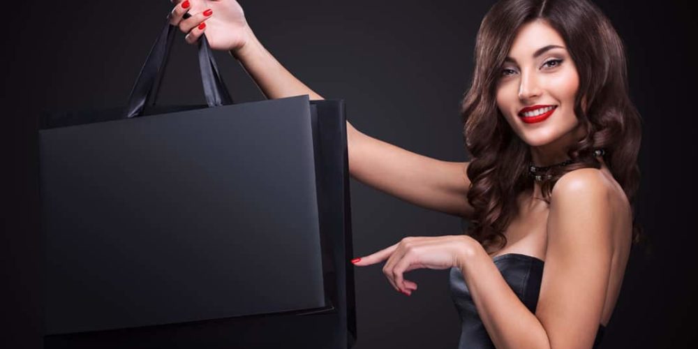 sac-papier-luxe-publicitaire-personnalisable-packaging-personnalise-print-emballages-b Une dame tenant des sacs papier luxe publicitaires personnalisables sur fond noir